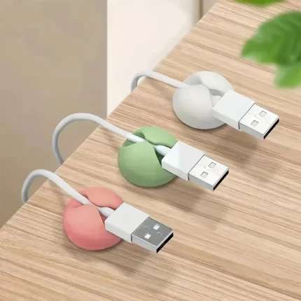 Multi-colored silicone adhesive cable management clips on a wooden desk.