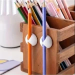 Multi-colored silicone adhesive cable management clips on a wooden desk.