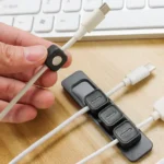 Magnetic cable organizer clips with adhesive base strip for desk.