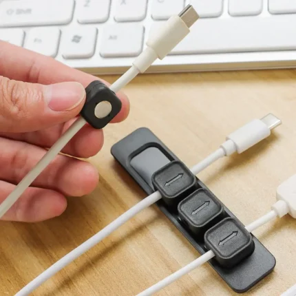 Magnetic cable organizer clips with adhesive base strip for desk.