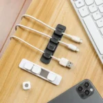 Magnetic cable organizer clips with adhesive base strip for desk.