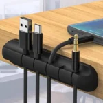 Black silicone cable organizer with adhesive backing holding multiple cords