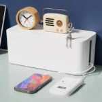 White smart cable management box, digital power monitor, charging phone.