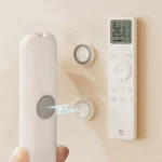 Magnetic adhesive wall mount holding a remote control and cable