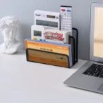 Black metal mesh desk organizer with three compartments holding office supplies.