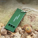 Olive green triple-tone survival whistle for emergency signaling.