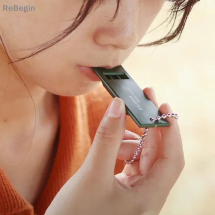 Olive green triple-tone survival whistle for emergency signaling.