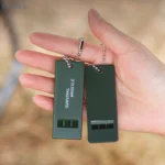 Olive green triple-tone survival whistle for emergency signaling.