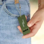 Olive green triple-tone survival whistle for emergency signaling.