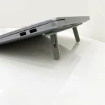 Slim adhesive foldable laptop stand elevating a black laptop.
