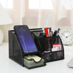 Black metal mesh desk organizer with smartphone holder and storage drawer.