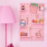 Pink pegboard wall organizer with shelves for cute collectibles.